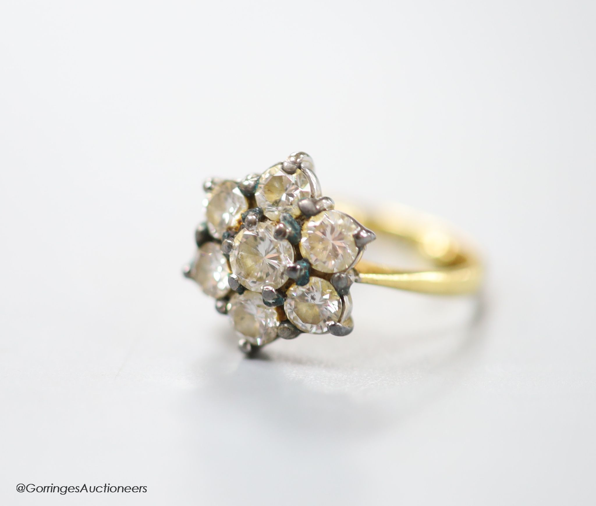 A modern 18ct gold and seven stone diamond cluster ring, size E (sizing spheres), gross weight 3.7 grams.